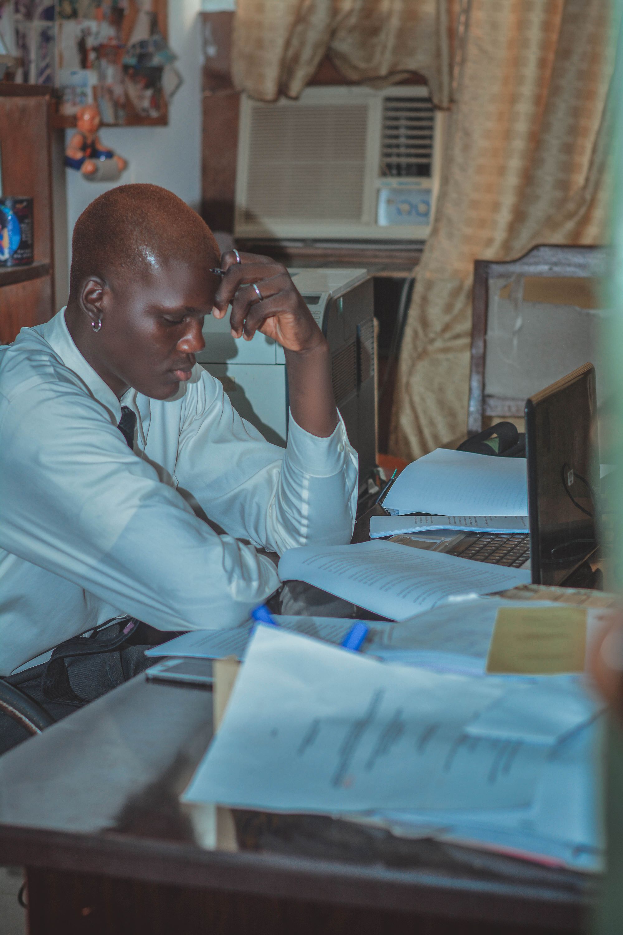 An office worker studies printed documents beside an open laptop