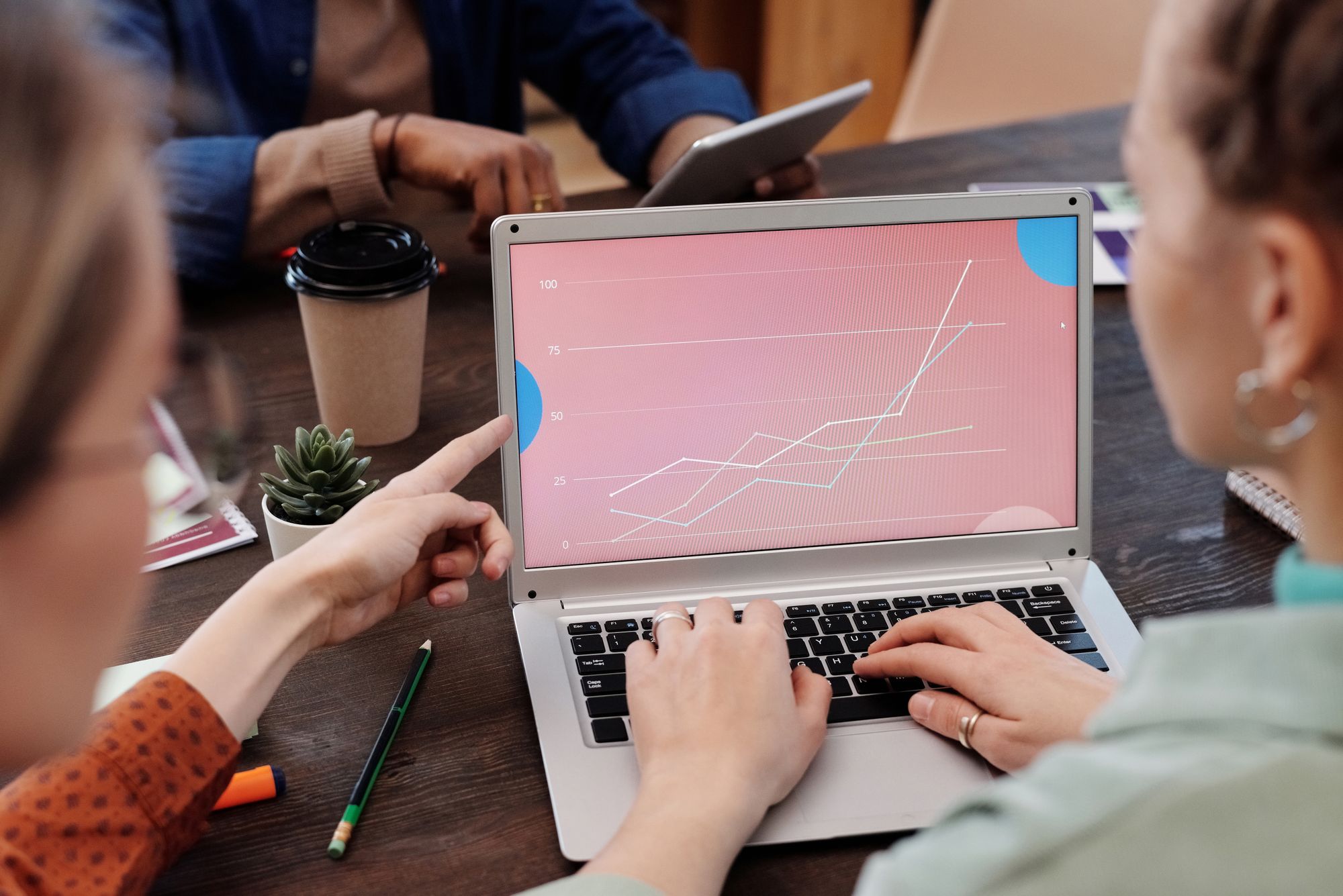 Coworkers compare a graph displayed on a laptop during a meeting