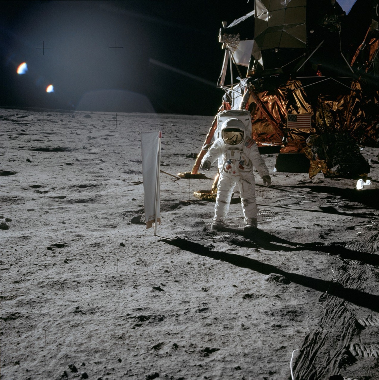 Buzz Aldrin stands on the lunar surface beside the fully deployed rectangular solar-wind foil collector and the Eagle lunar module