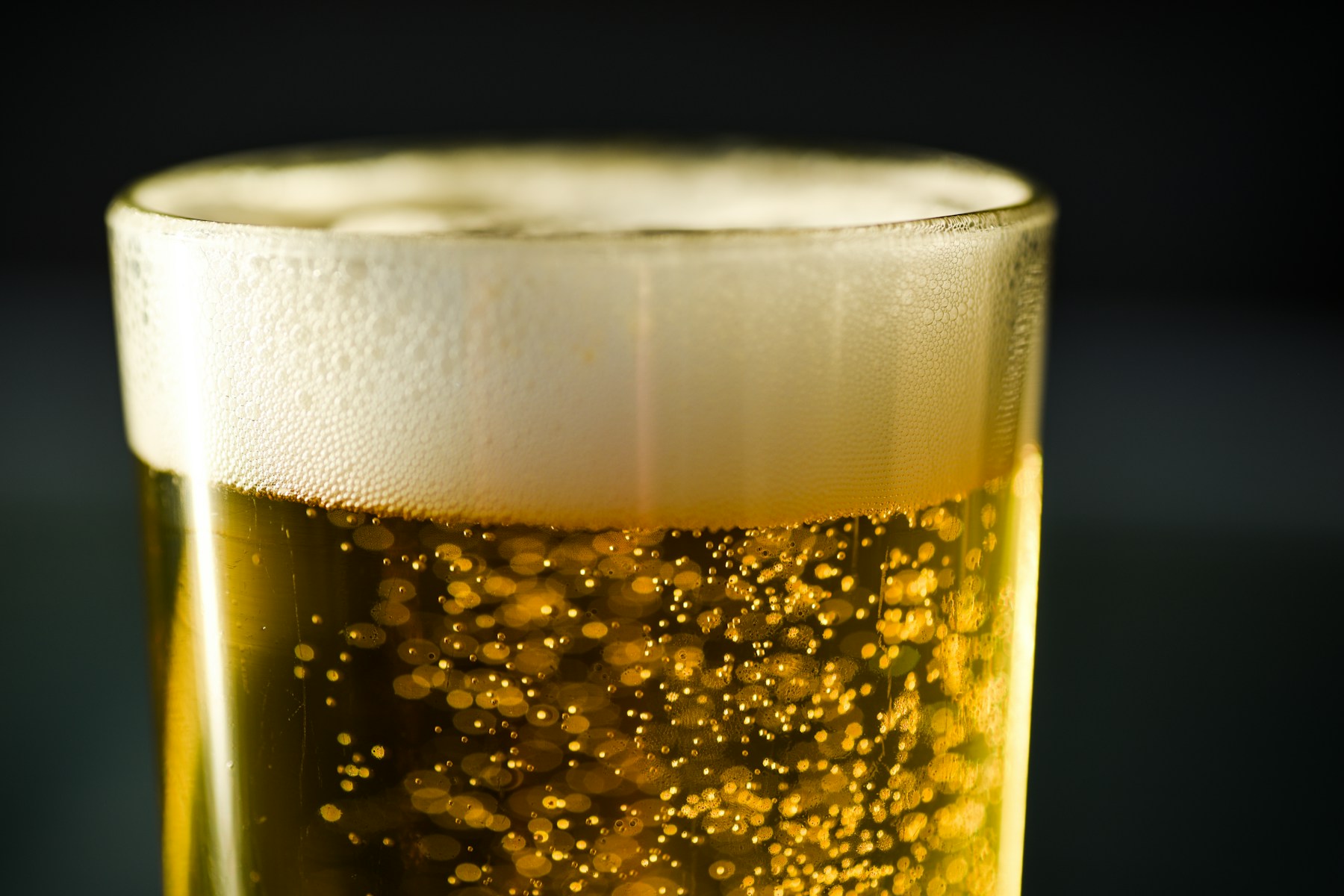 Carbon dioxide bubbles rising through a clear glass of lager