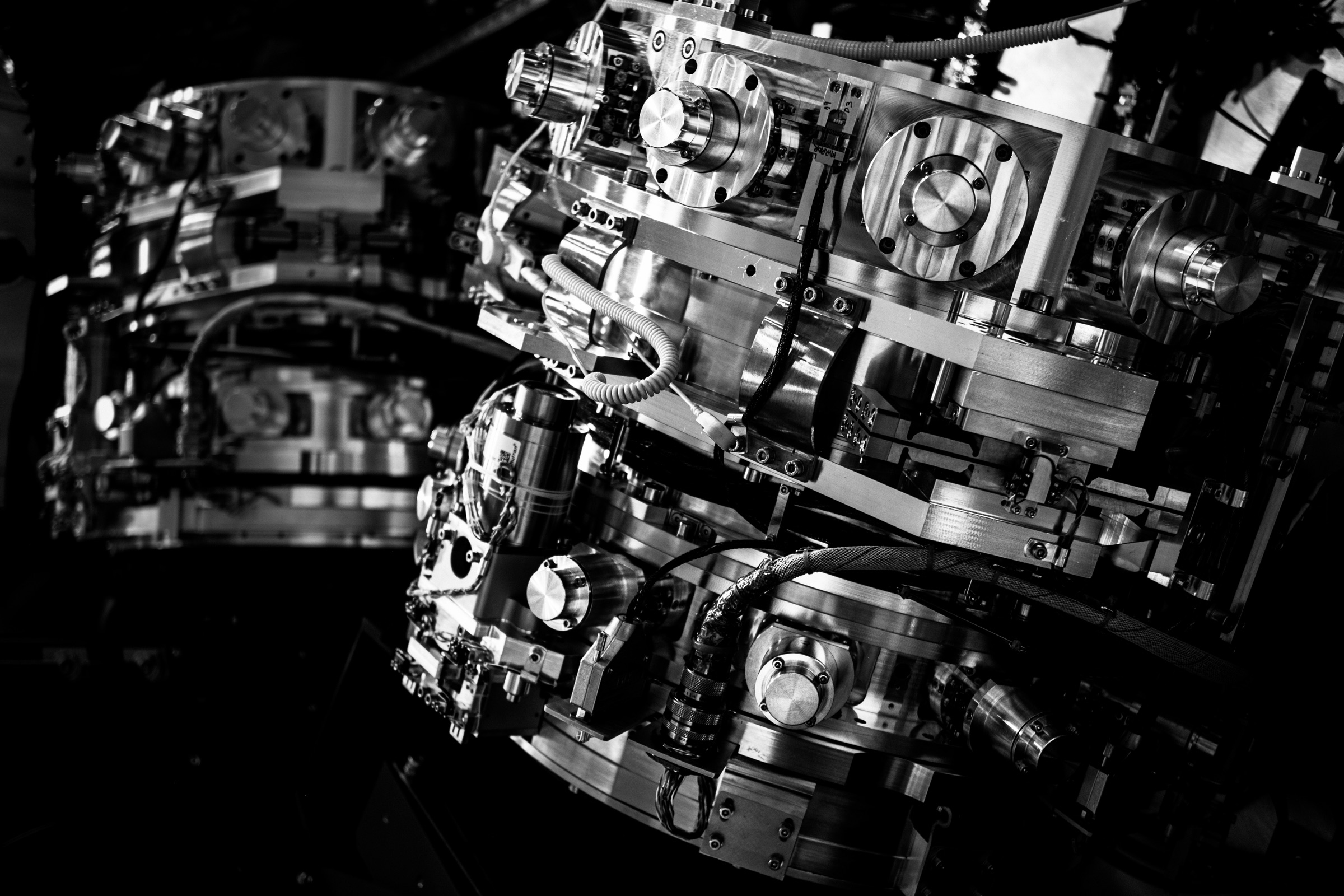 Two tiered metal infrared camera assemblies covered in bolts and cables hang inside the dark interior of the MOONS instrument