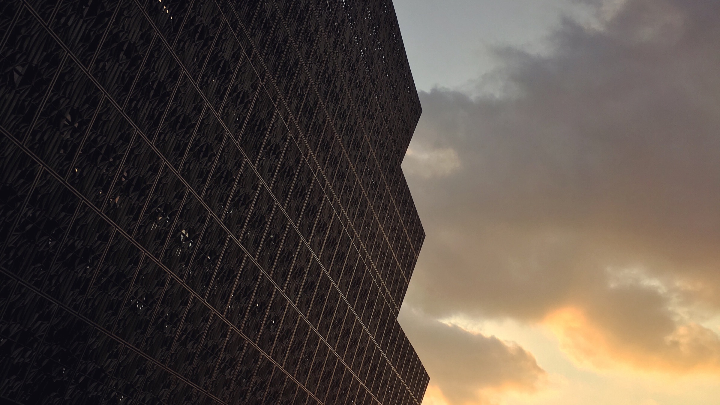 The bronze-patterned exterior of the National Museum of African American History and Culture against a glowing sunset
