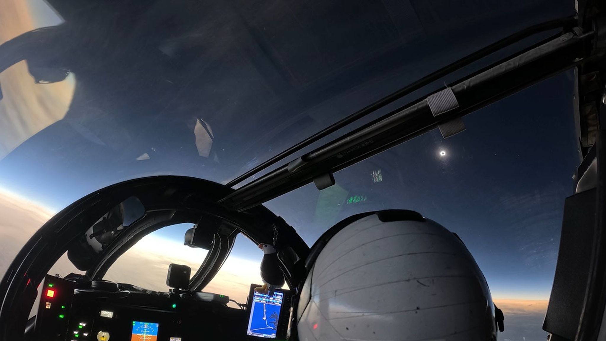 The darkened Sun and its corona seen from a NASA WB-57 cockpit, with three planets visible in the eclipse-darkened sky and a bright horizon below