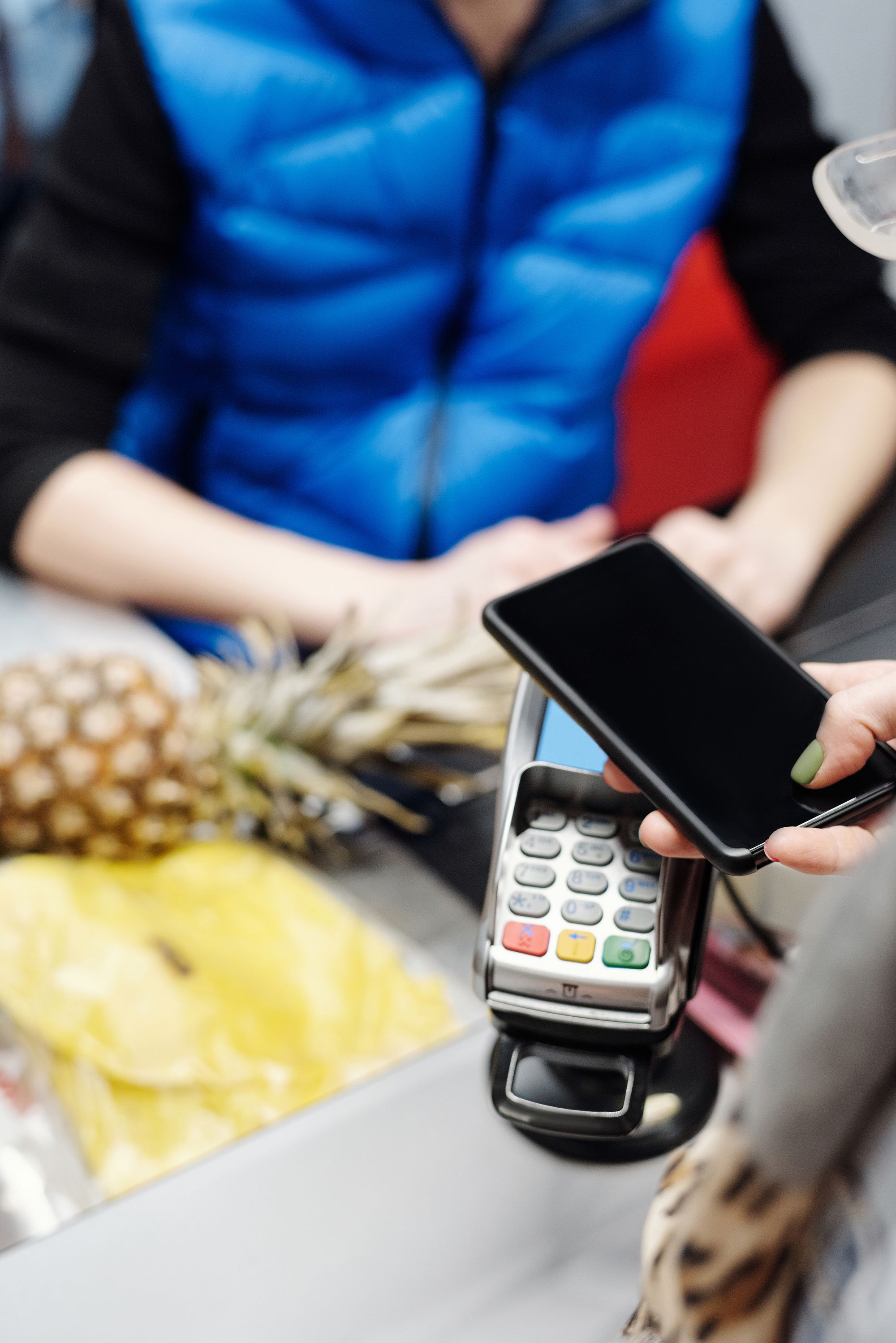 A customer holds a smartphone near a payment terminal at a grocery checkout