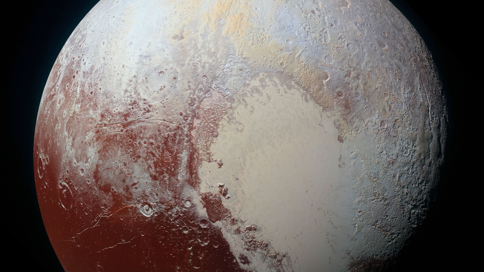 An enhanced-color New Horizons view of Pluto showing pale blue, yellow, orange, and red terrain with the bright heart-shaped Tombaugh Regio at lower right