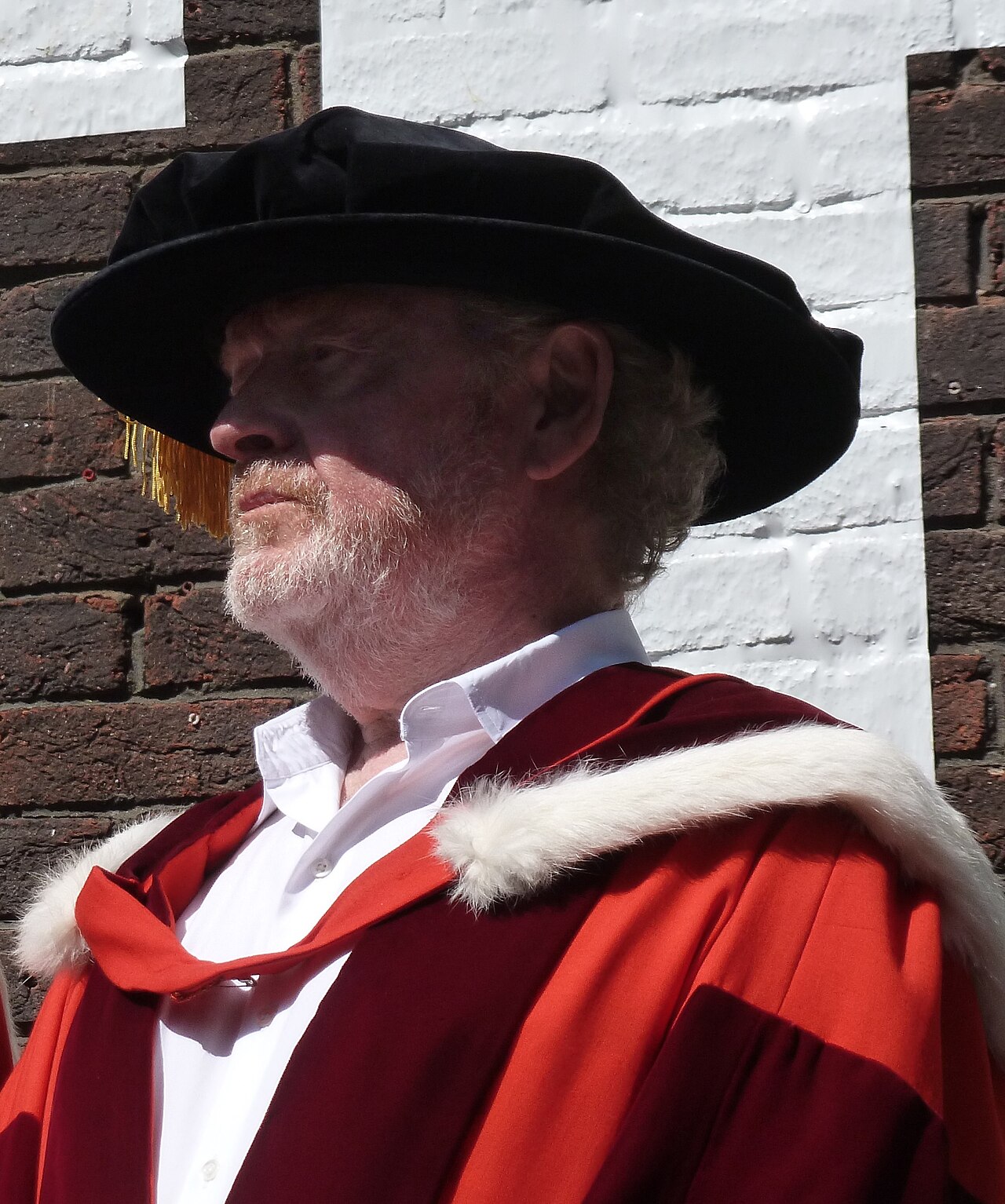 Film director Ridley Scott wears a ceremonial red robe and black cap outdoors