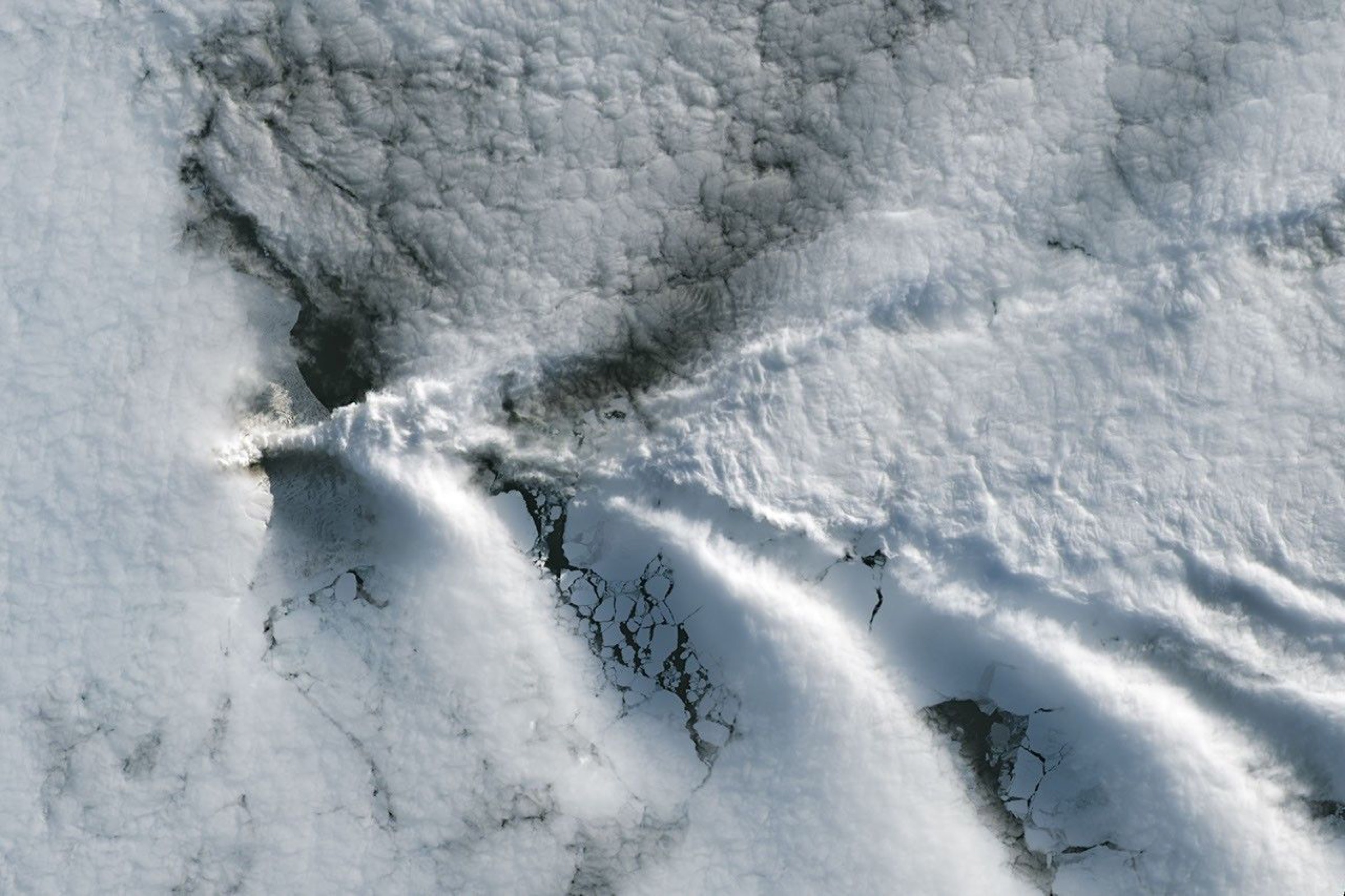 Landsat satellite view of V-shaped wave clouds stretching across the ocean downwind of snow-covered Saunders Island