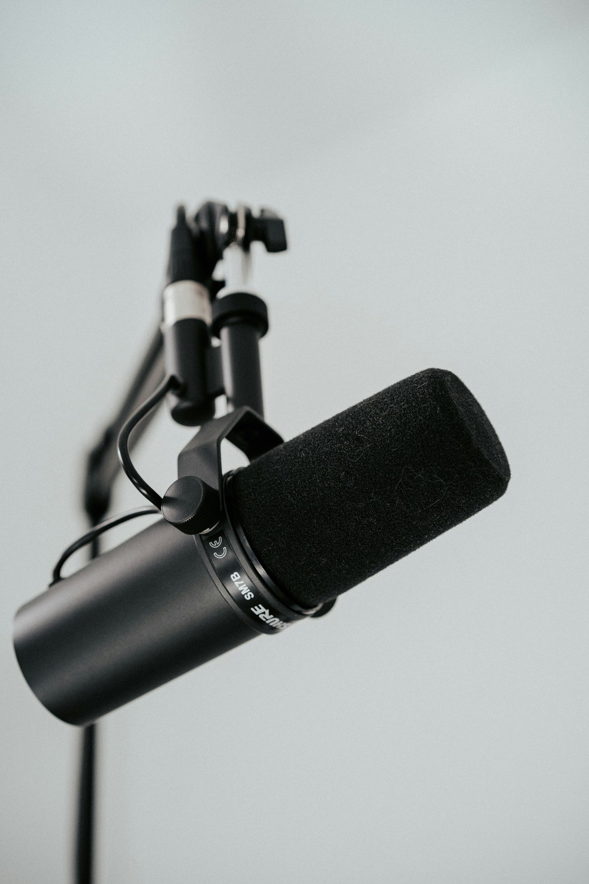 A black studio microphone stands against a gray background