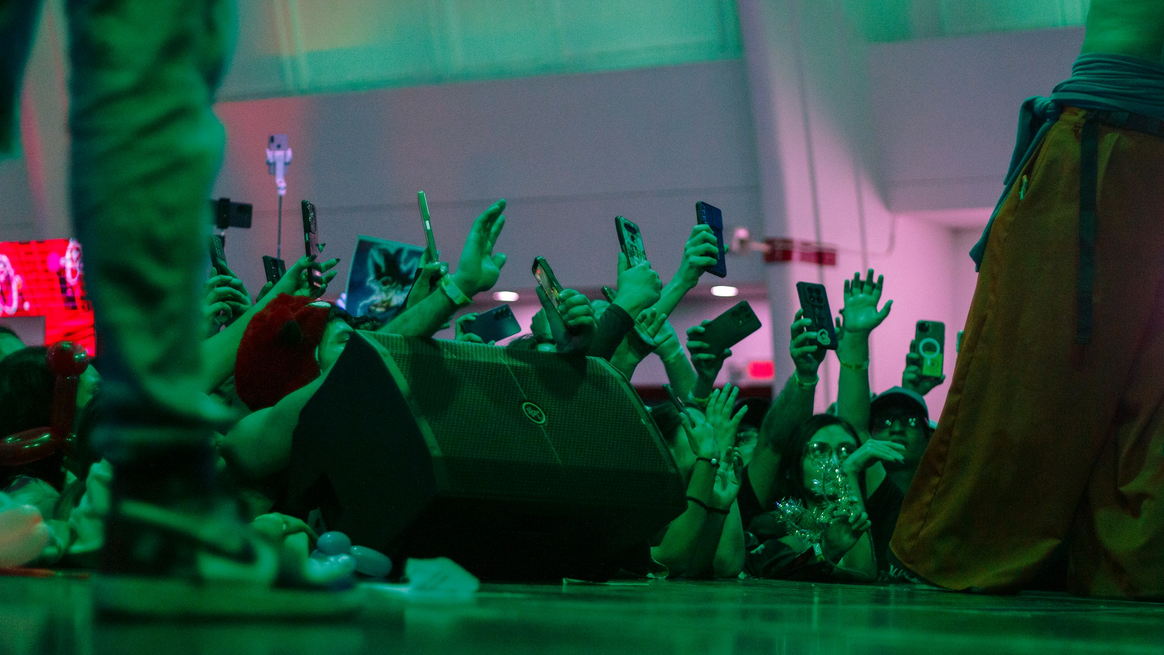 Concert fans reach toward a stage while holding up their phones